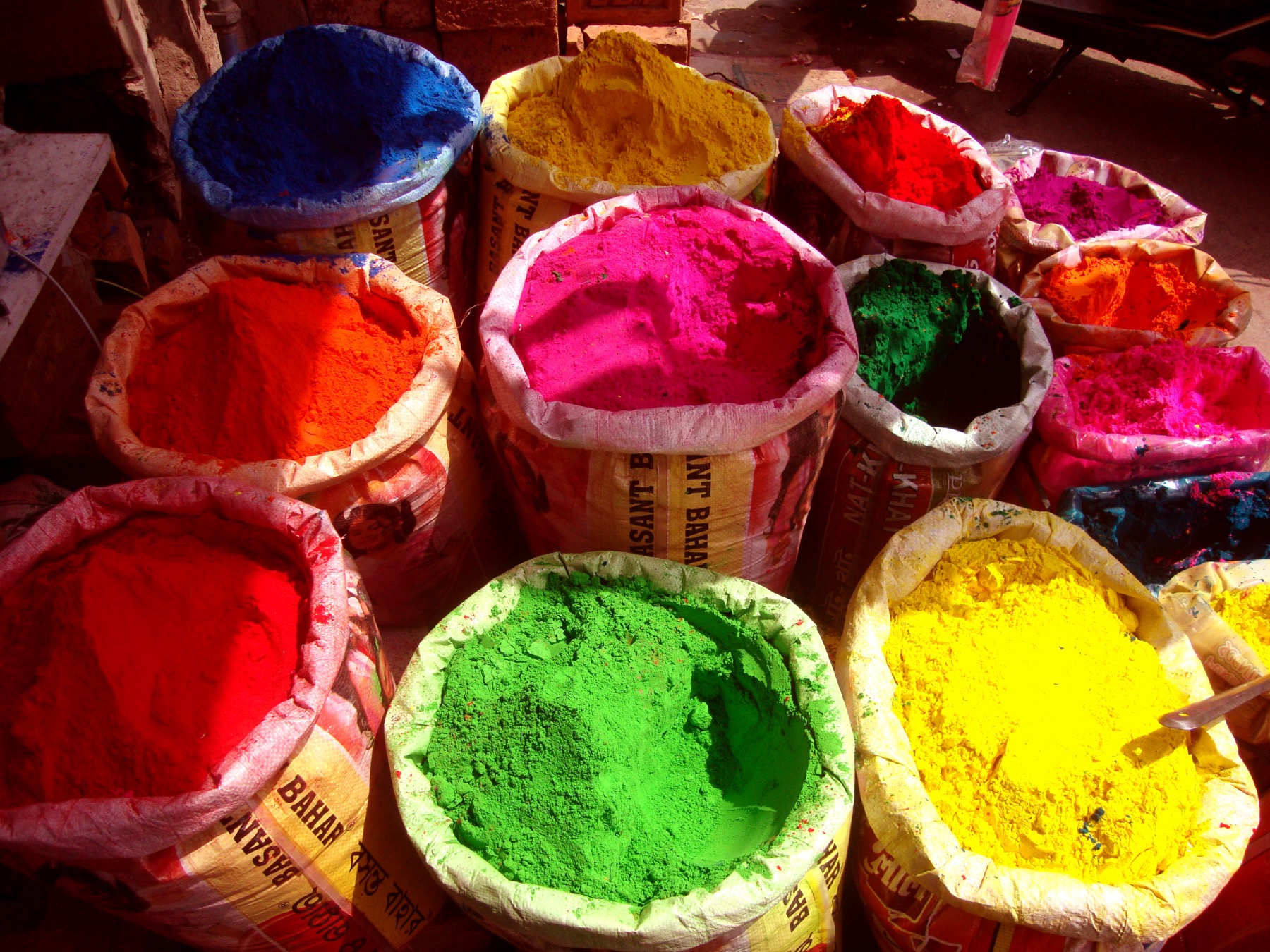 Stacked tins and heaps of powder colors at a Holi shop.