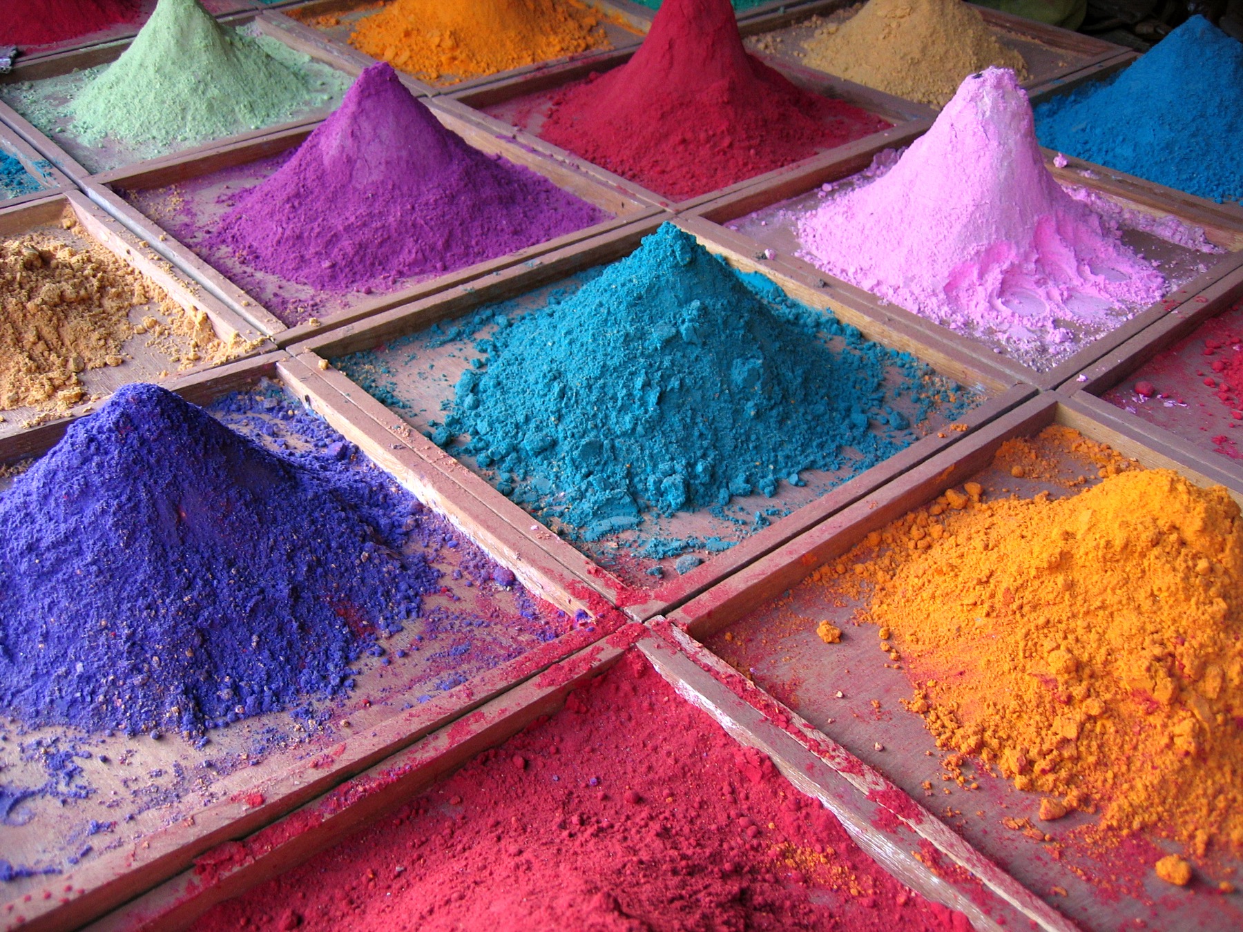 Open sacks of bright powdered pigments for sale on a market stall in Goa, India.